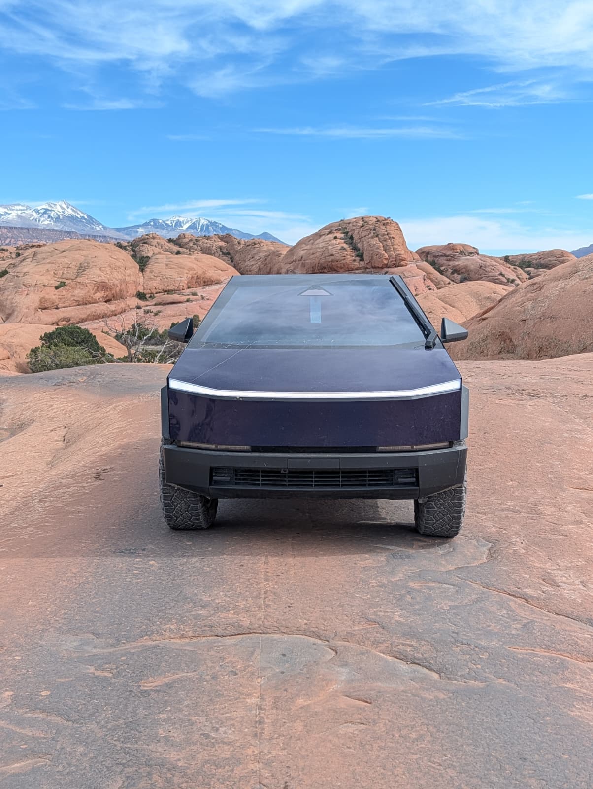 Cybertruck head-on with LED light bar and snow-capped mountains